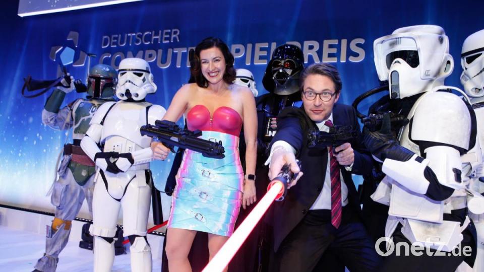 Andreas Scheuer (rechts), Bundesverkehrsminister, steht mit einem Laserschwert neben Dorothee Bär, Staatsministerin für Digitalisierung, zwischen Sturmtruppen aus den Star-Wars-Filmen beim Deutschen Computerspielpreis im Admiralspalast. Bild: Gerald Matzka/dpa