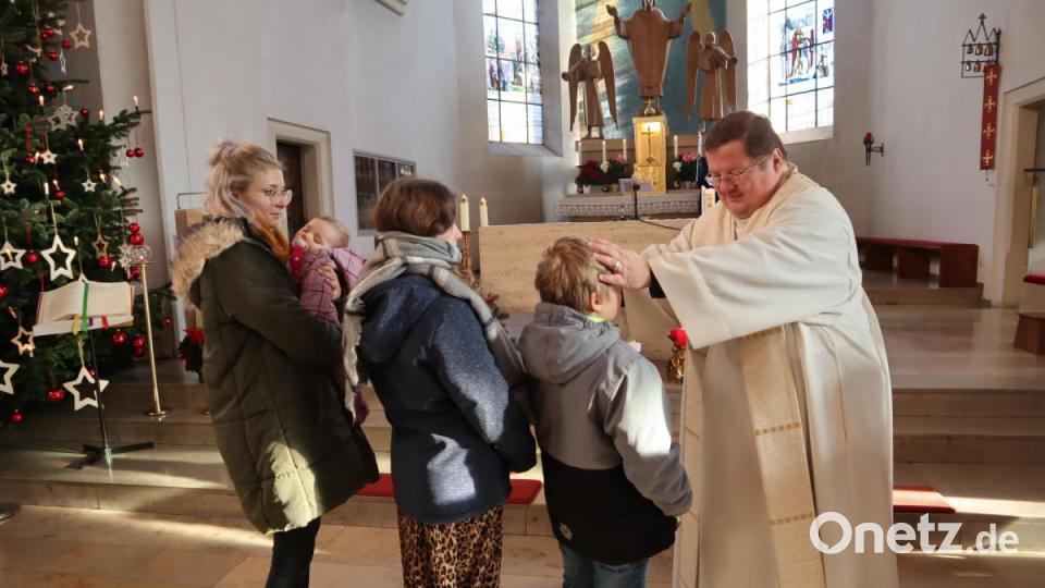 Stadtpfarrer Hubert Bartel segnet nach dem Gottesdienst die Kinder - egal ob bereits selbst auf den Beinen oder getragen auf den Armen der Eltern, hellwach oder schlafend. Bild: wrm