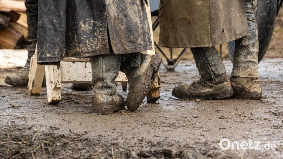 Teilnehmer des Elefantentreffens stehen Schlamm bedeckt auf dem Gelände im Schlamm. Bild: Armin Weigel/dpa