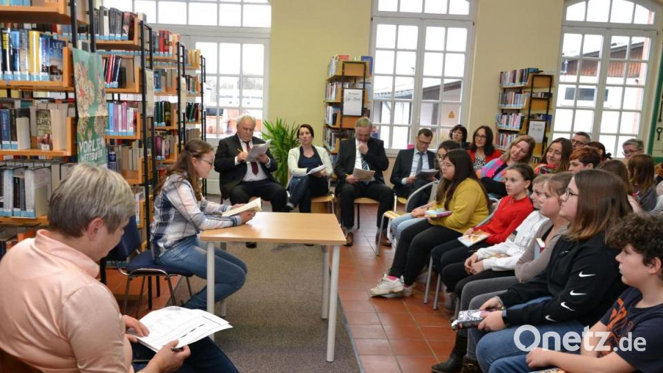Regina Werner liest aus dem Buch &quot;Meine beste Freundin, der Catwalk und ich&quot; von Autorin Dagmar Hoßfeld. Büchereichefin Cornelia Kolzenburg (links), die Jurymitglieder (hinten) und die Schüler, Eltern und Lehrer im Publikum hören gespannt zu. Bild: sfo