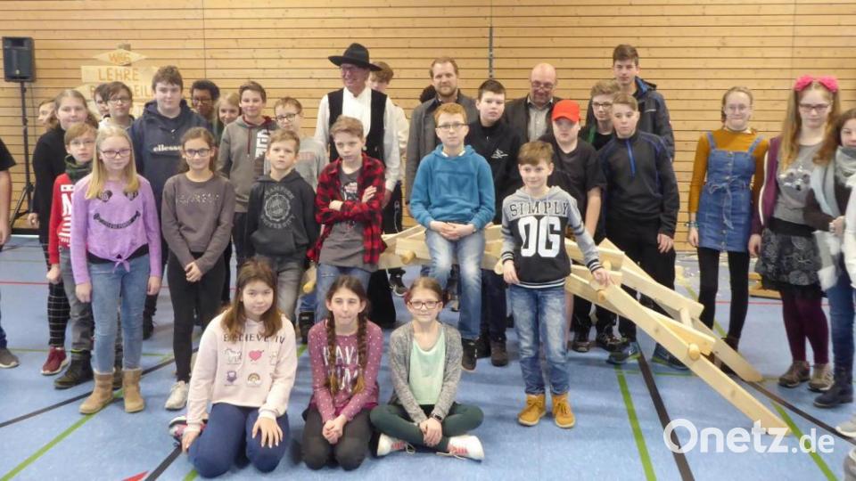 Gruppenbild einiger begeisterter Schüler mit der Holzbrücke sowie (hinten von links) Zimmermann Richard Betz (mit Hut), Innungsobermeister Adrian Blödt und Rektor Günther Paul Bild: fsb