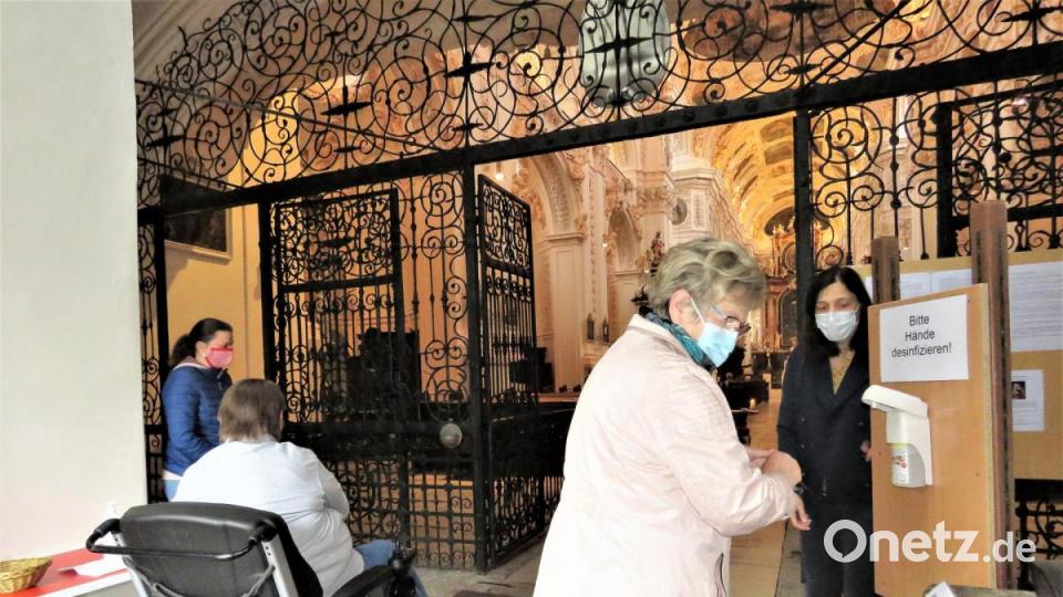 Waltraud Illmann (rechts hinten) und Stefanie Siller (links hinten) zeigen den Gläubigen, wie das Desinfektionsmittel benutzt wird. Bild: ubb