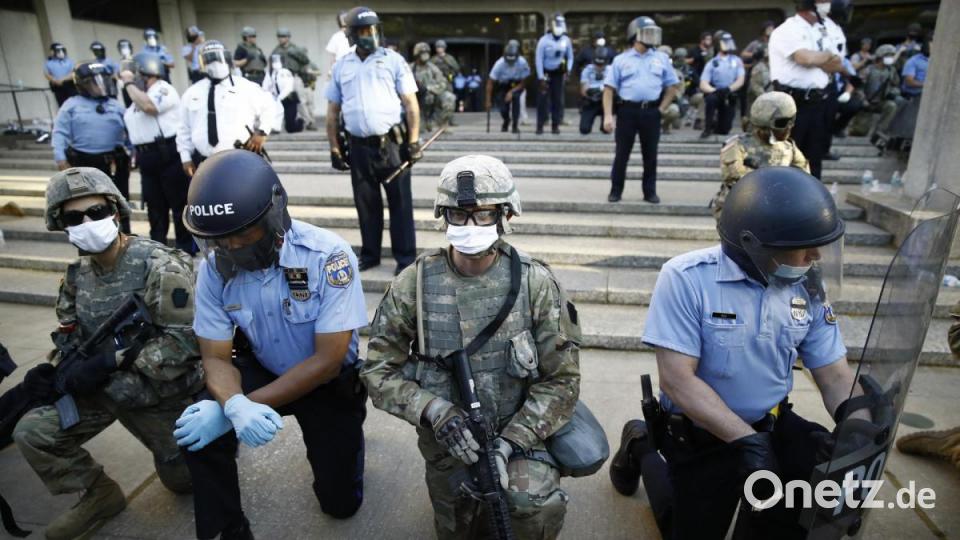 Mitarbeiter der Polizei von Philadelphia und der Nationalgarde von Pennsylvania knien vor dem Polizeihauptquartier während eines Protestmarsches. Bild: Matt Rourke/AP/dpa
