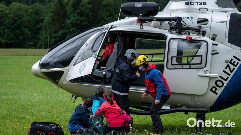 Einsatzkräfte der Polizei und der Bergwacht lassen die erste Familie, die sie mit dem Hubschrauber von der Höllentalangerhütte (Grainau, Landkreis Garmisch-Partenkirchen) gerettet haben, im Tal aus der Maschine. Rund 60 Wanderer saßen nach dem schweren Unwetter in der Nacht auf der Hütte fest und mussten mit dem Hubschrauber zurückgeholt werden. Wegen beschädigter Brücken konnten sie nicht zu Fuß in das Tal zurückkehren. Bild: Jörg Jowy/Bayerisches Rotes Kreuz/dpa