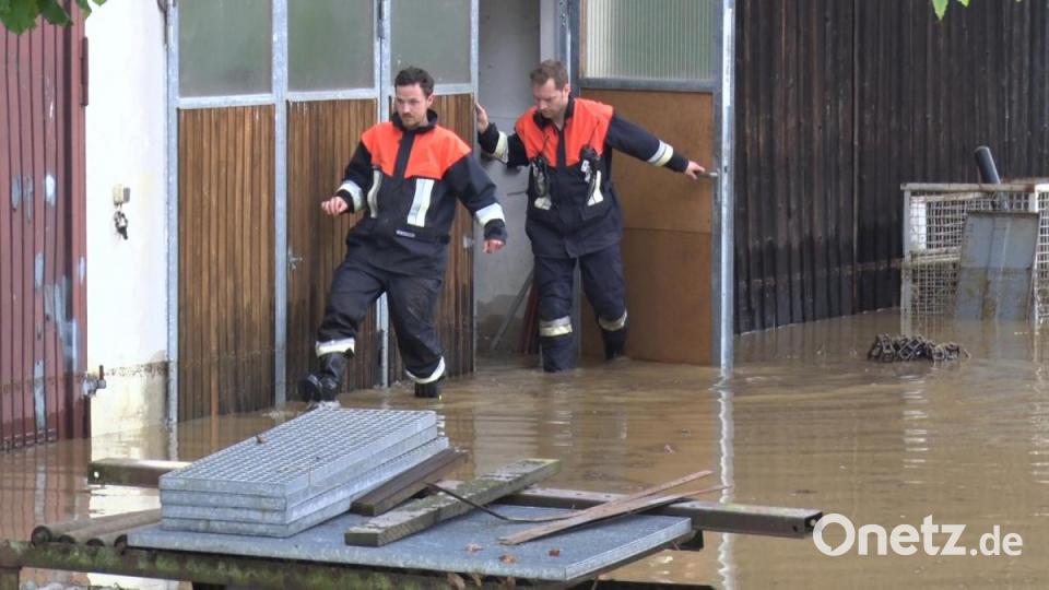 Feuerwehrmänner verlassen ein unter Wasser stehendes Gebäude in Hagendorf bei Waidhaus. Heftige Unwetter haben im Landkreis Neustadt an der Waldnaab für zahlreiche Überschwemmungen gesorgt. Bild: Bernd März/dpa