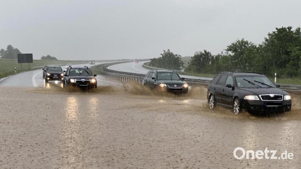 Autos fahren bei starkem Regen auf der zum Teil unter Wasser stehenden Autobahn 6 bei Wieselrieth (Landkreis Neustadt/WN). Heftige Unwetter haben im Landkreis Neustadt an der Waldnaab für zahlreiche Überschwemmungen gesorgt. Bild: Bernd März/dpa