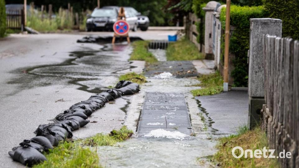 Wasser quillt über die Ränder eines kleinen Grabens an einer Straße im Ortsteil Hammersbach, einer Gemeinde in Grainau (Landkreis Garmisch-Partenkirchen). In der Nacht waren bereits gut 200 Bewohner vorsorglich in Sicherheit gebracht worden, nachdem ein Bach über die Ufer getreten und eine Mure abgegangen war. Bild: Matthias Balk/dpa