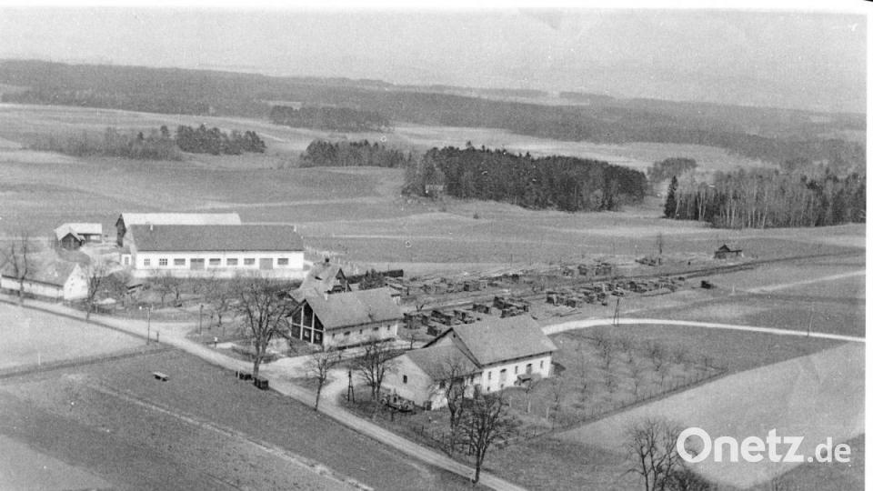 Diese Luftaufnahme aus dem Jahr 1958 zeigt die damals noch &quot;einsame Lage&quot; des Bahnhofes Ursensollen und der beiden Lagerhäuser südlich des Ortskernes. Westlich der AS 4 findet sich nun das Edeka-Geschäft, südlich zum Beispiel die Firma KTM. Die Abzweigung zur AS 15 in Richtung Hohenkemnath verlief zu dieser Zeit noch mitten durch beide Lagerhausteile. Das Holzlager beim Bahnhof erinnert noch an die West-Erweiterung des Truppenübungsplatzes Hohenfels im Jahre 1951. Damals durften die abgelösten Bauern noch einige Monate in ihren Wäldern einen Holzabschlag durchführen, der Holzhändler aus ganz Deutschland anlockte. Im Hintergrund ist die ehemalige Halle der Firma Ehebauer zu sehen. Später war hier die Firma Schmieding. Nun - seit 2008 - ist hier die Firma &quot;Dr. Dr. Eberth, Arzneimittel&quot; angesiedelt. Bild: Bildarchiv der Gemeinde Ursensollen