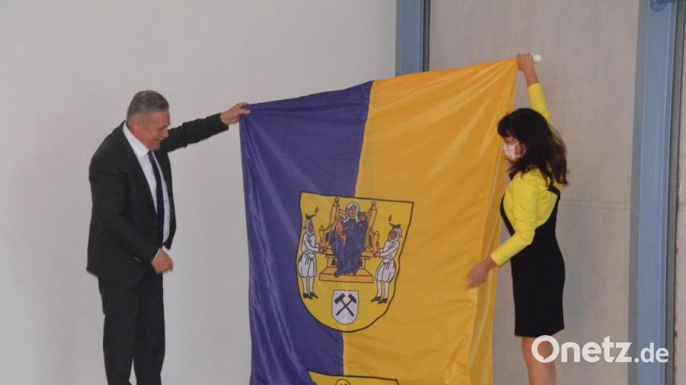 Oberbürgermeister Rolf Schmidt und Katrin Bräuer enthüllen ein Präsent aus Annaberg-Buchholz: Die Fahne mit dem Stadtwappen. Bild: Kunz