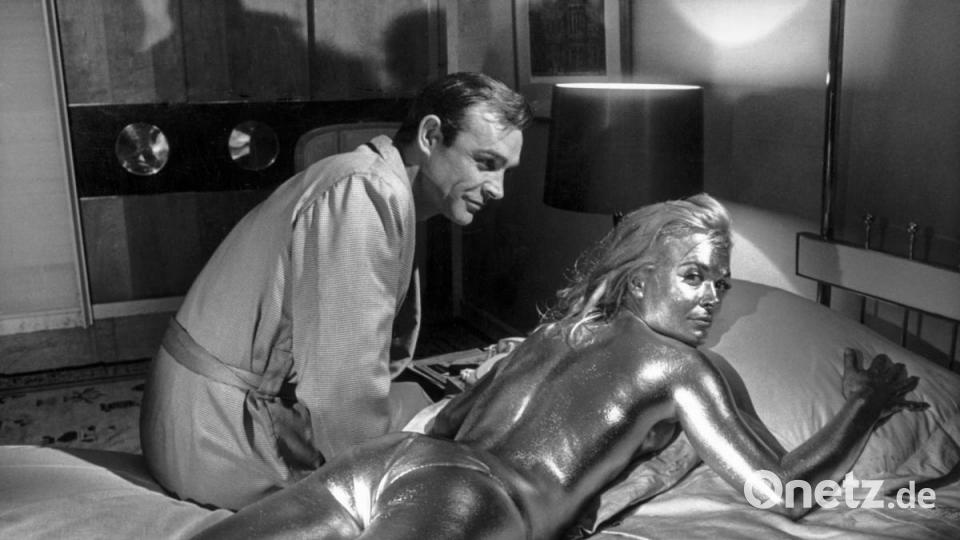 Sean Connery in der Rolle des James Bond und die goldüberzogene Shirley Eaton, aufgenommen während der Dreharbeiten zum James-Bond-Film &quot;Goldfinger&quot; im Jahre 1964. Bild: Str/KEYSTONE/dpa