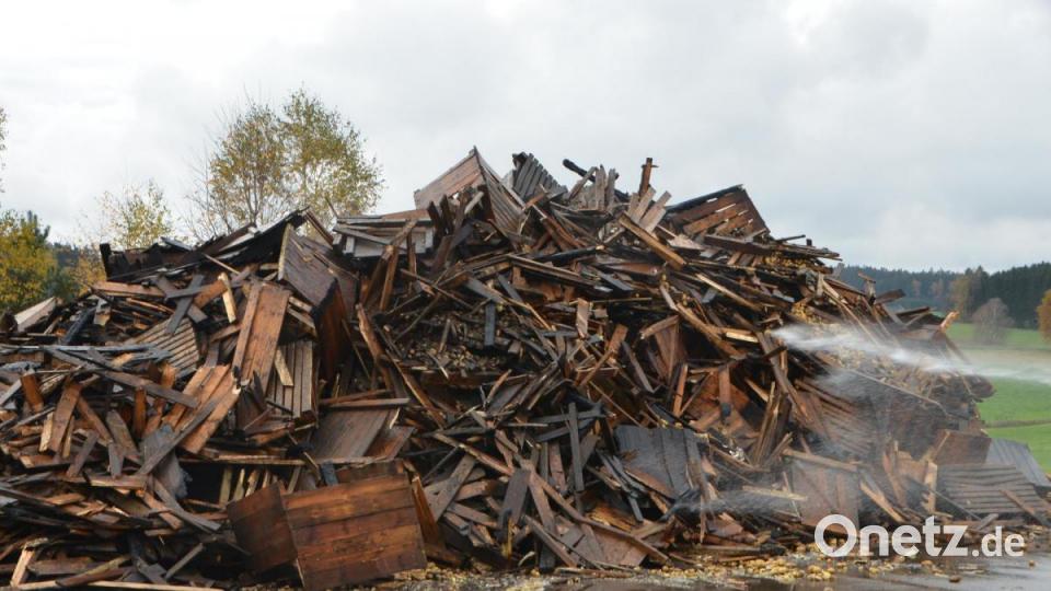 Nur noch verkohlte Bretter bleiben von den Kartoffelkisten übrig, die noch immer von der Feuerwehr mit Wasser benetzt werden. Bild: dob