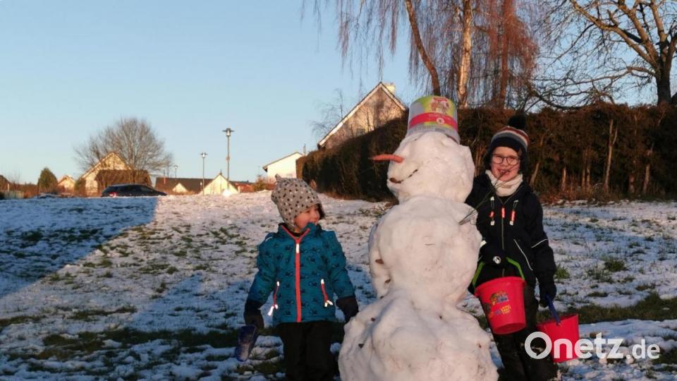 Ob dieser Schneemann in Schieflage noch lange in die Sonne lacht? Florian (rechts) und Marius holen mit ihren Eimerchen neuen Schnee herbei. Bild: Portner
