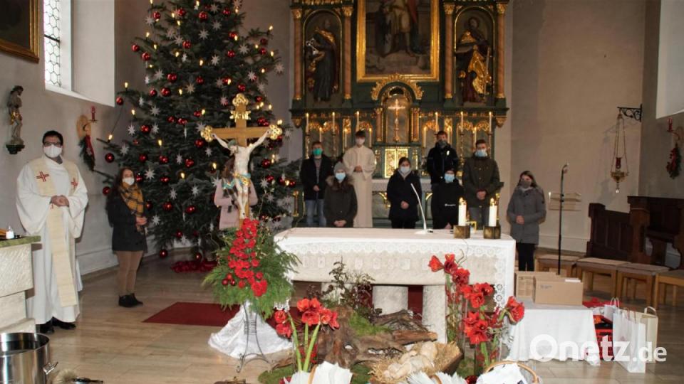 Pfarrer Wolfgang Dietz (links) segnete in Schönsee die vor dem Altar aufgestellten Dreikönigspäckchen, die unter Leitung von Gemeindereferent Christian Glaser (Fünfter von rechts) von den Buben und Mädchen verpackt wurden. Bild: mmj