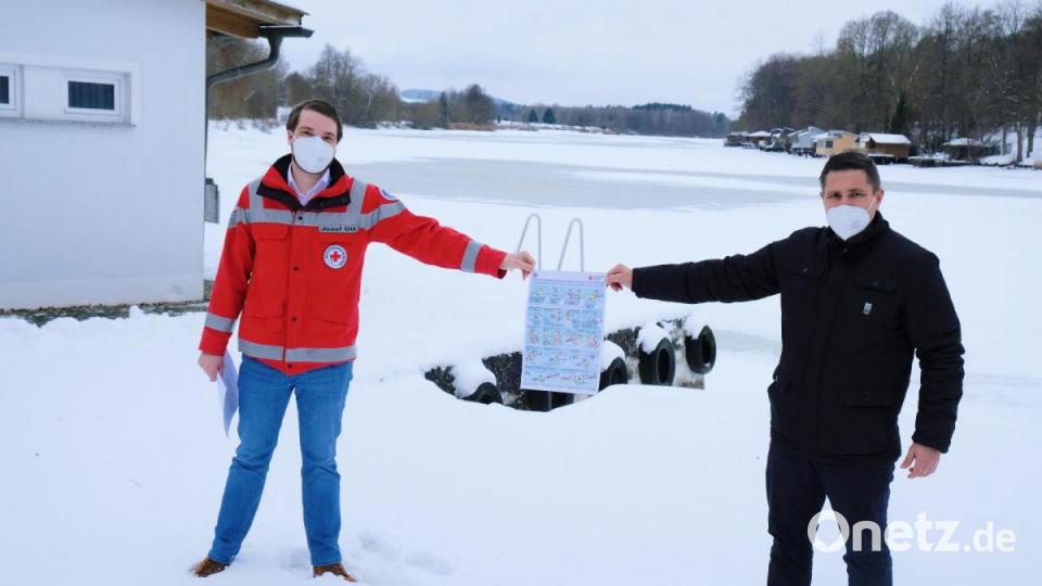 Zugefrorener Rußweiher: Auf seiner Eisfläche ist Vorsicht geboten, warnten am Ufer des Freizeitsees Wasserwacht-Chef Josef Ott (links) und Bürgermeister Marcus Gradl. Wasserwacht-Plakate mit Symbolbildern sollen vor den Gefahren auf dem Eis warnen und geben Tipps für das richtige Verhalten bei einer Notrettung Bild: do