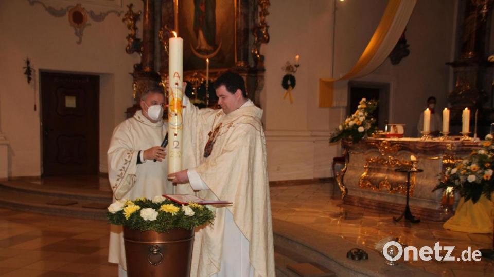 Durch das Eintauchen der Osterkerze und Segensgebete, weihte Kaplan Florian Fronhöfer (rechts), assistiert von Kaplan Ulli Wabra, das Taufwasser Bild: frd