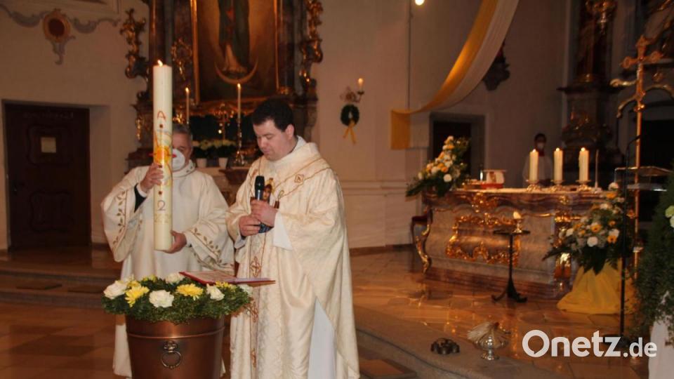 Durch das Eintauchen der Osterkerze und Segensgebete, weihte Kaplan Florian Fronhöfer (rechts), assistiert von Kaplan Ulli Wabra, das Taufwasser Bild: frd