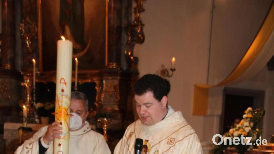 Durch das Eintauchen der Osterkerze und Segensgebete, weihte Kaplan Florian Fronhöfer (rechts), assistiert von Kaplan Ulli Wabra, das Taufwasser Bild: frd
