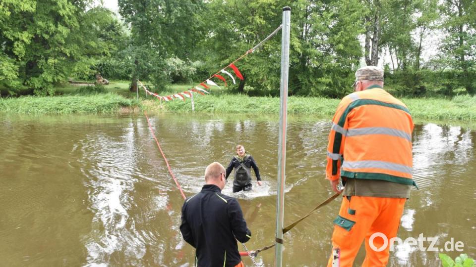 Bauhof-Mitarbeiter zogen eine Absperrleine über den Flussarm, der das Ende der Badezone markiert. Bild: hcz