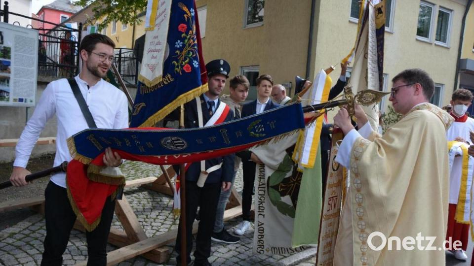 Neupriester Bastian Neumann heftet ein Erinnerungsband an die Fahne des TSV Konnersreuth. Bild: jr