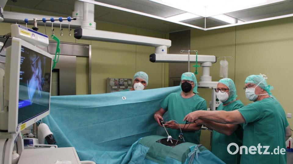 Professor Karl-Heinz Dietl überlässt Dr. Bernhard Kürner und Kemnaths Bürgermeister Roman Schäffler die Führung bei einem „laparoskopischen Eingriff“ (minimal-invasive Chirurgie) an einer Playmobil-Figur. Tobias Frank, Leiter der Notaufnahme, schaut über den Vorhang hinweg aufmerksam zu (von rechts). Bild: Kliniken Nordoberpfalz, Michael Reindl/exb