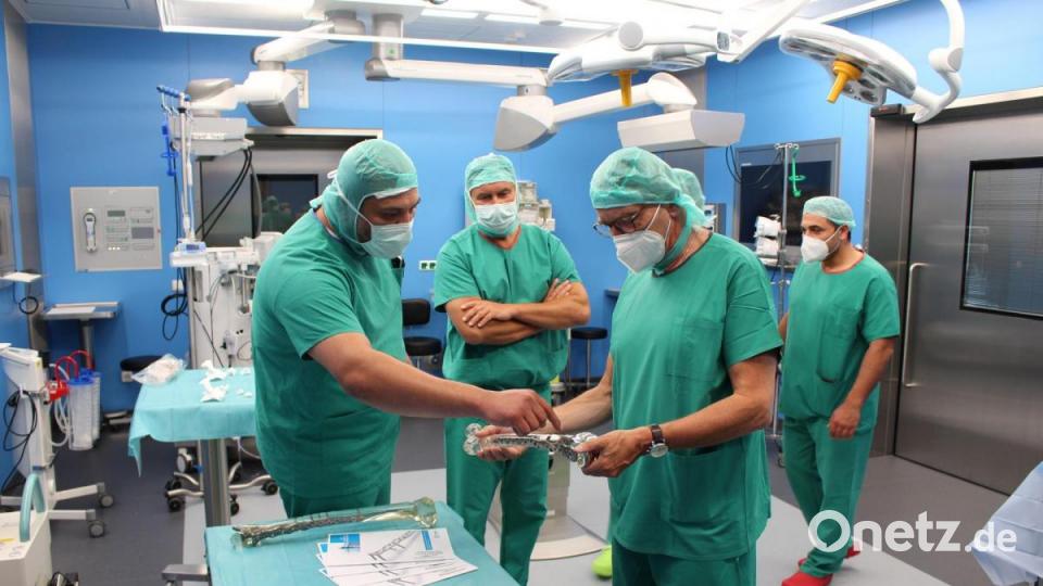 Ein Facharzt der Klinik für Unfallchirurgie (links) zeigt Bürgermeister Franz Stahl (rechts) einen künstlichen Oberschenkelknochen. In der Mitte: Chefarzt Dr. Thomas Neubauer-Gartzke. Bild: Kliniken Nordoberpfalz, Michael Reindl/exb