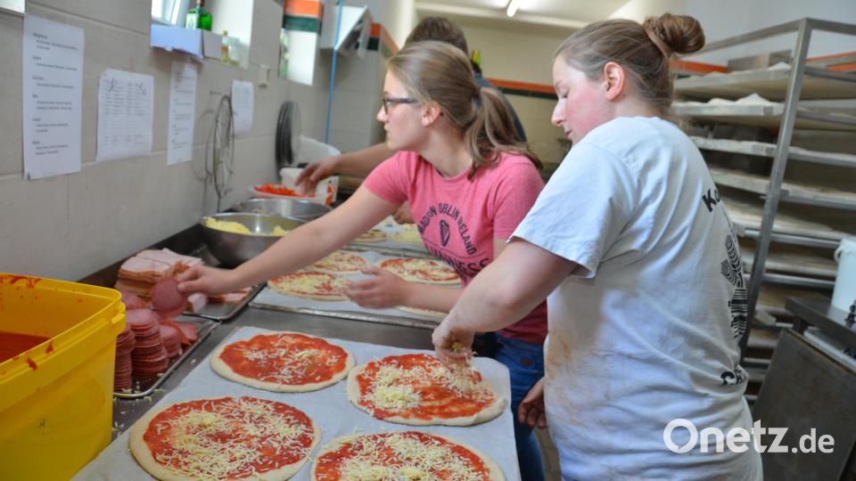 Im Eiltempo belegen die Helfer Pizzen. Bild: doj