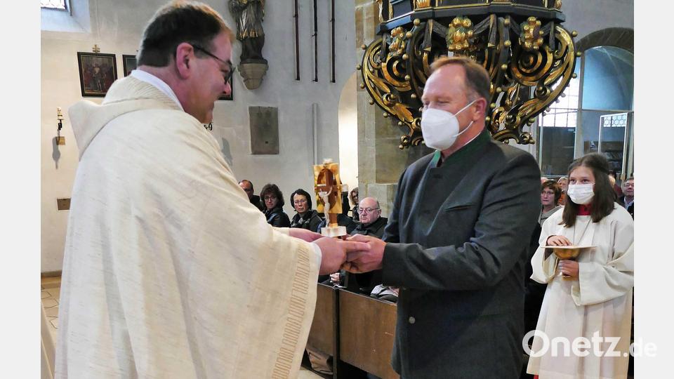 Ein Vertreter aus Pfarrer Maders letzter Wirkungsstätte in Bad Kötzting bringt das Abschiedsgeschenk der Gemeine; ein Kreuz für den Altar, das nach einem Entwurf des Pfarrers geschaffen wurde. Bild: wbe