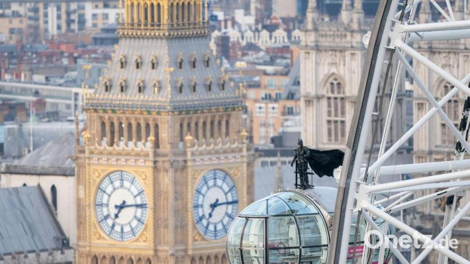 Ein als Superheld Batman verkleideter Mann fährt stehend auf einer Gondel des London Eye mit. Bild: Dominic Lipinski/PA Wire/dpa