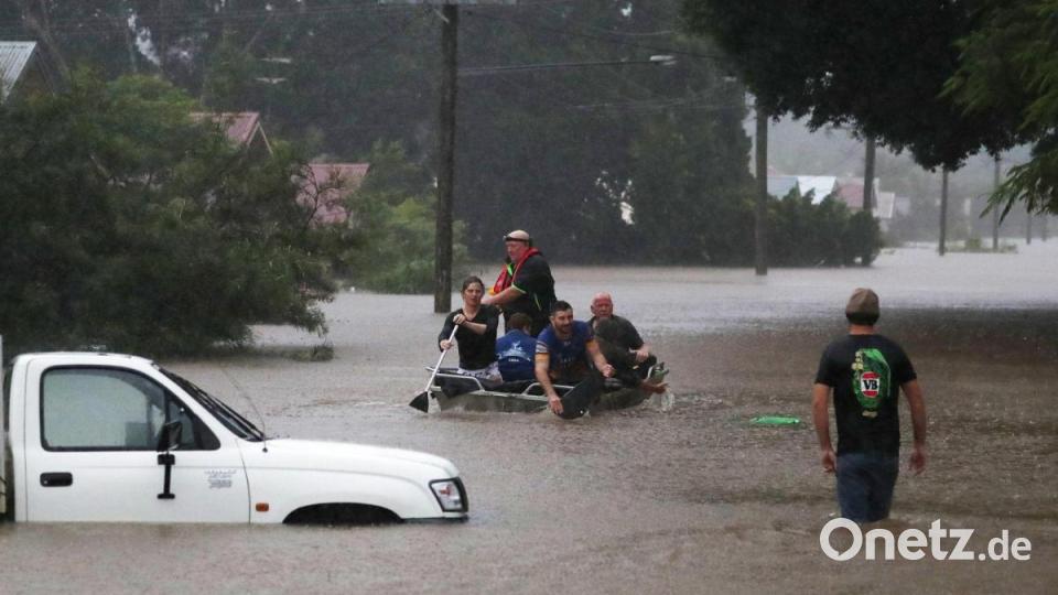 Menschen rudern im australischen Lismore auf einer überschwemmten Straße. Tausende mussten nach sinftlutartigem Regen in Sicherheit gebracht werden. Das Land leidet besonders unter dem Klimawandel. Bild: Jason O’brien/AAP/dpa