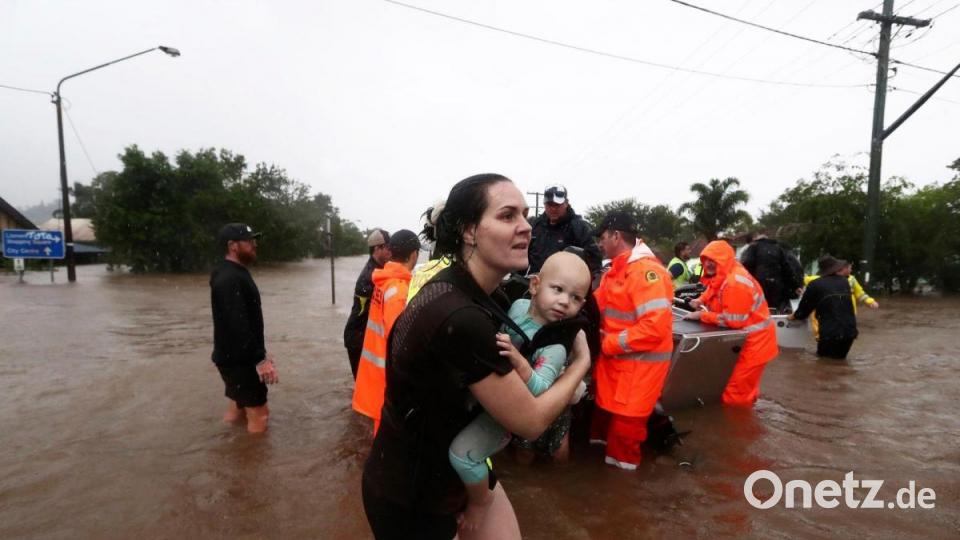 Eine Frau im australischen Lismore sucht mit Baby Schutz vor den Fluten.  Sintflutartiger Regen hat die schweren Überschwemmungen im Osten Australiens weiter verschärft. Bild: Jason O'brien/AAP/dpa