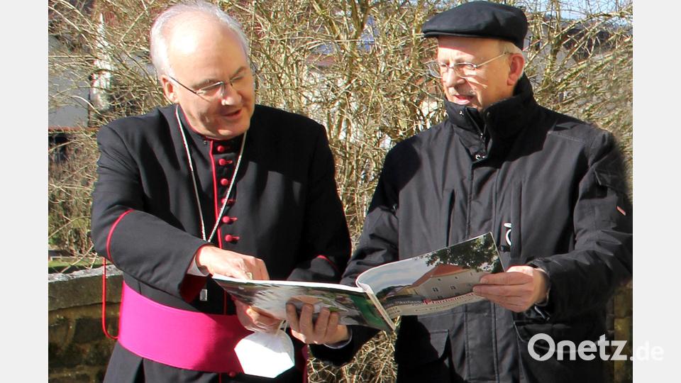 Noch vor dem Betreten des Pfarrheims informierte Pfarrer Herbert Rösl anhand einer Bilddokumentation Bischof Rudolf Voderholzer über die einzelnen Bauphasen des Projekts. Bild: Josef Böhm