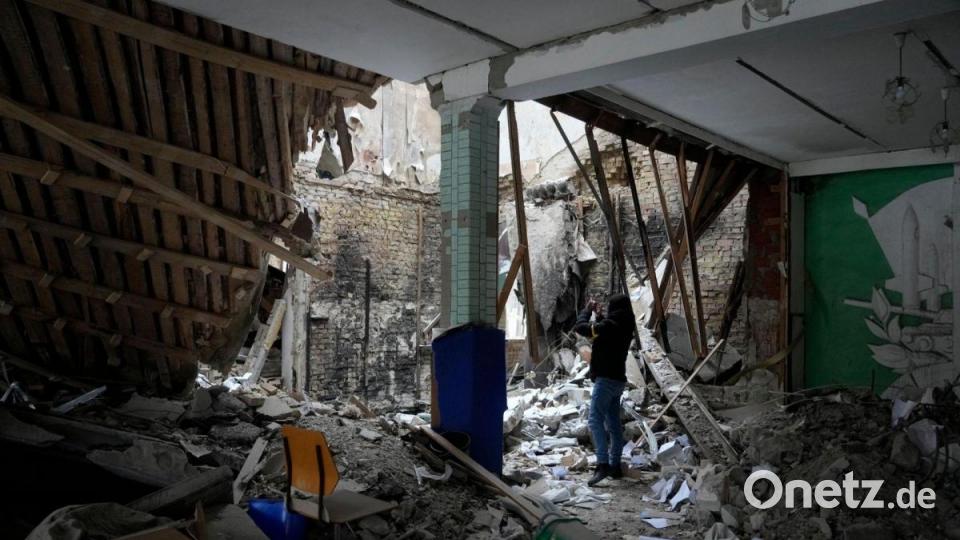 Eine Frau fotografiert ein zerstörtes Unterkunftsgebäude in der Nähe eines Kontrollpunktes in Brovary. Bild: Efrem Lukatsky/AP/dpa