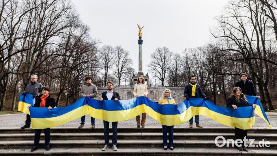 Freie Wähler, Linke, Grüne, CSU, FDP und SPD: Mehrere bayerische Politiker tragen während einer überparteilichen Aktion für die Ukraine ein langes Banner in den Farben der ukrainischen Landesflagge. Bild: Matthias Balk/dpa