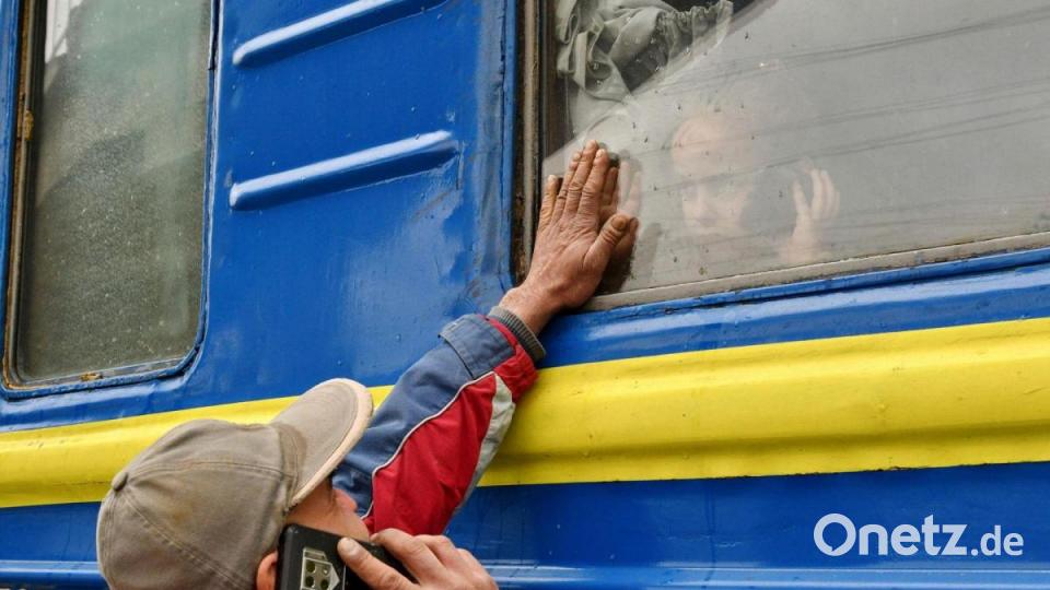 Ein Mann verabschiedet sich von einem Kind, das auf die Abfahrt in Richtung Westukraine wartet. Bild: Andriy Andriyenko/AP/dpa