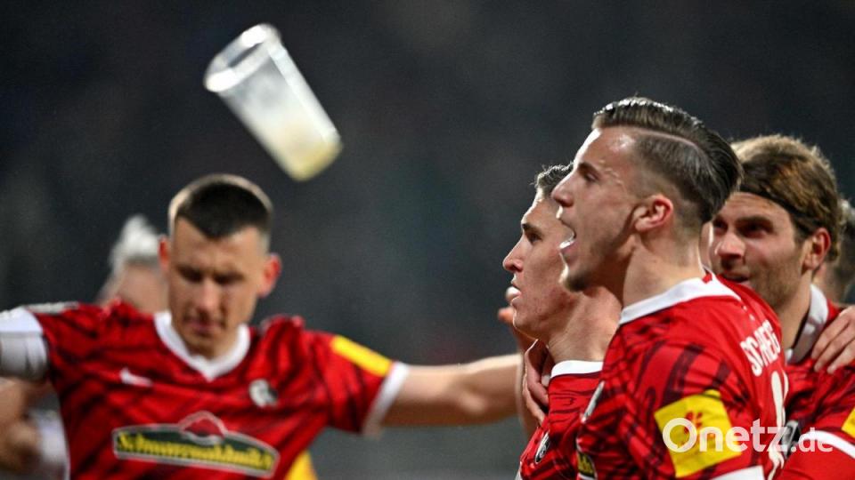 Freiburgs Spieler werden nach dem Tor zum 1:2 mit Bierbechern beworfen. Bild: David Inderlied/dpa