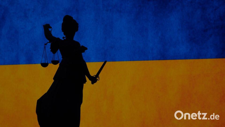 Friedensdemonstration in Frankfurt - und Justitia auf dem Gerechtigkeitsbrunnen zeichnet sich vor einer Ukraine-Flagge ab. Bild: Sebastian Gollnow/dpa