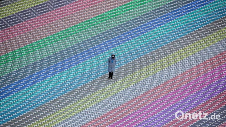 Vor der Eröffnungsfeier der Paralympics geht eine Person über das bunte Feld des Pekinger Olympiastadion „Vogelnest“. Bild: Christoph Soeder/dpa