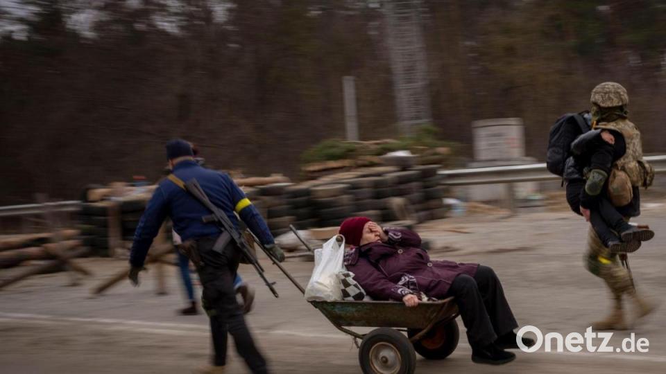 Ein ukrainischer Soldat hilft einer fliehenden Dabei bei der Überquerung des Flusses Irpin in den Außenbezirken von Kiew. Bild: Emilio Morenatti/AP/dpa
