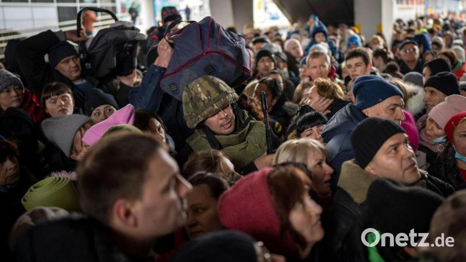 Ein ukrainischer Soldat versucht, die Menschenmenge aufzulösen, die am Bahnhof von Kiew in einen Zug nach Lwiw steigen will. Bild: Emilio Morenatti/AP/dpa