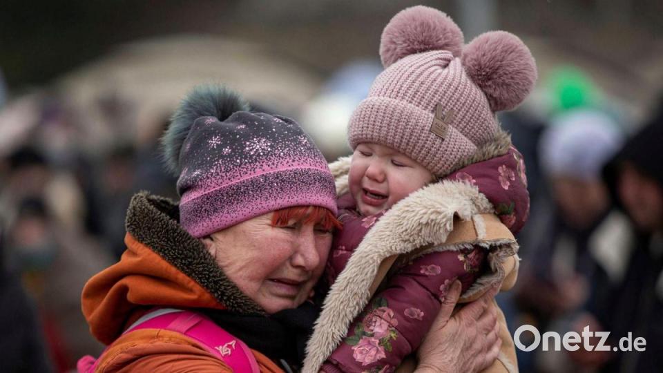 Eine weinende Frau mit einem Kind im Arm am Grenzübergang im polnischen Medyka. Bild: Visar Kryeziu/AP/dpa