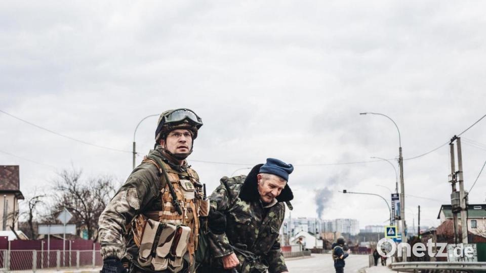 Ein ukrainischer Soldat in Irpin hilft einem älteren Mann, die Straße zu überqueren. Bild: Diego Herrera/EUROPA PRESS/dpa