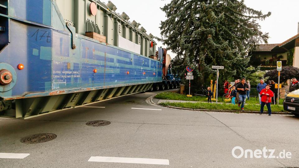 An der Ecke Dachelhofer-/Fichtenstraße lassen sich rund ein Dutzend Zuschauer das Spektakel nicht entgehen. Der graue Transformator schwebt in seinem Transportgestell über dem Asphalt, eine Zugmaschine steht schon in der Fichtenstraße. Bild: Hösamer