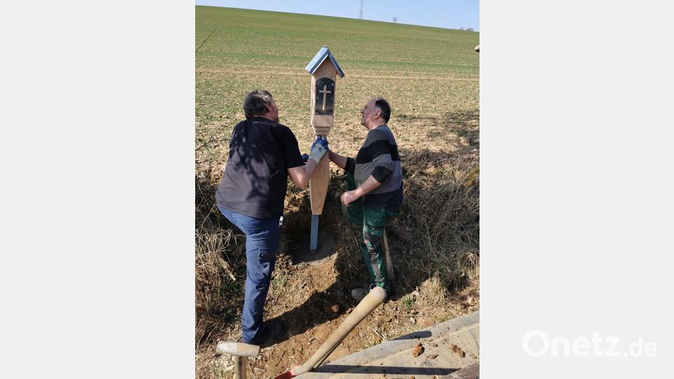 In gemeinsamer Arbeit wird das Feldkreuz aufgestellt. Bild: hzi
