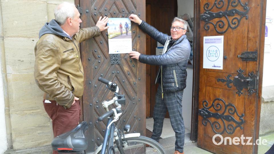 Fördervereinsvorsitzender Hans-Peter Pauckstadt-Künkler (links) und Bürgermeister und Routenkoordinator Reinhold Wildenauer bringen an der Pforte der Michaelskirche die Einladung zum Simultankirchenfest an. Bild: Kunz