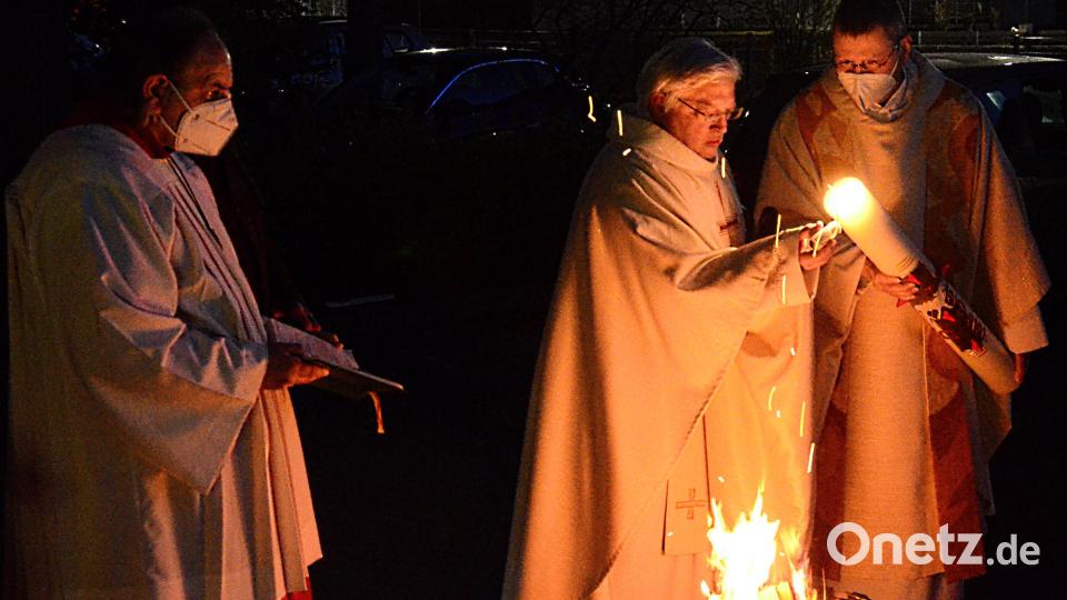 Stadtpfarrer Gottfried Schubach (Mitte) und Pfarrvikar Reinald Bogensperger (rechts) entzünden die Osterkerze am Osterfeuer. Bild: Kunz