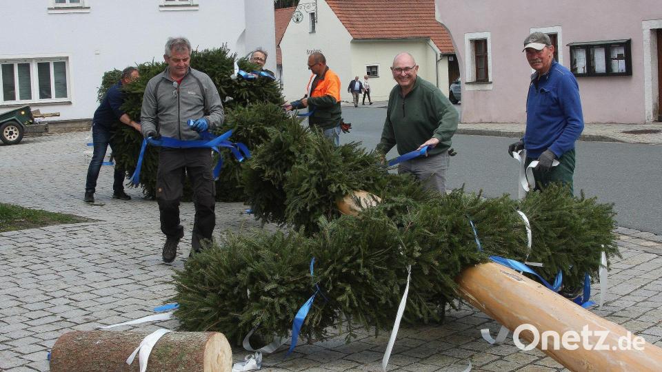 Damit die Arbeit in Falkenberg zügig von der Hand geht, schnappt sich jeder eines der Bänder, um sie an die Kränze zu knoten. Bild: wro