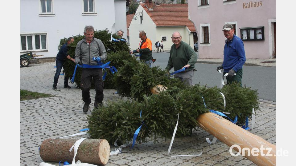 Damit die Arbeit in Falkenberg zügig von der Hand geht, schnappt sich jeder eines der Bänder, um sie an die Kränze zu knoten. Bild: wro