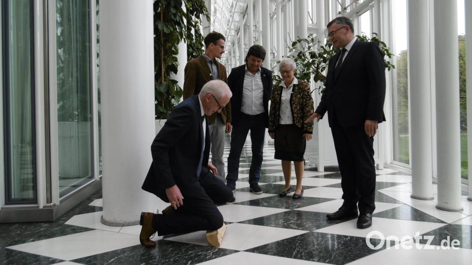 Der Hahnbacher Bürgermeister Bernhard Lindner geht beim traditionellen Patenbitten in der Staatskanzlei auf einem Holzscheitel auf die Knie. Jürgen Huber, Säm Kraus und Marianne Moosburger (hinten, von links) beobachten genau die Reaktion von Staatsminister Florian Herrmann. Bild: mma