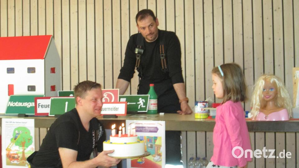 Brennende Kerzen auf der Torte sind nicht ungefährlich: Die Feuerwehrleute Johannes Sperer und Daniel Kircher zeigten im Kindergarten, worauf es ankommt. Bild: Kerstin Pflaum/exb