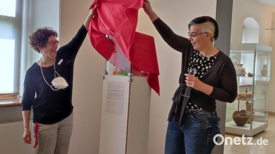 Museumsleiterin Stefanie Dietz und Roxane Bicker enthüllen das Gastobjekt. Bild: Lilija Kremenchuttskaya (IKM Weiden)/exb